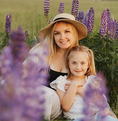 A mother and daughter smiling at the camera in a field of lavendar