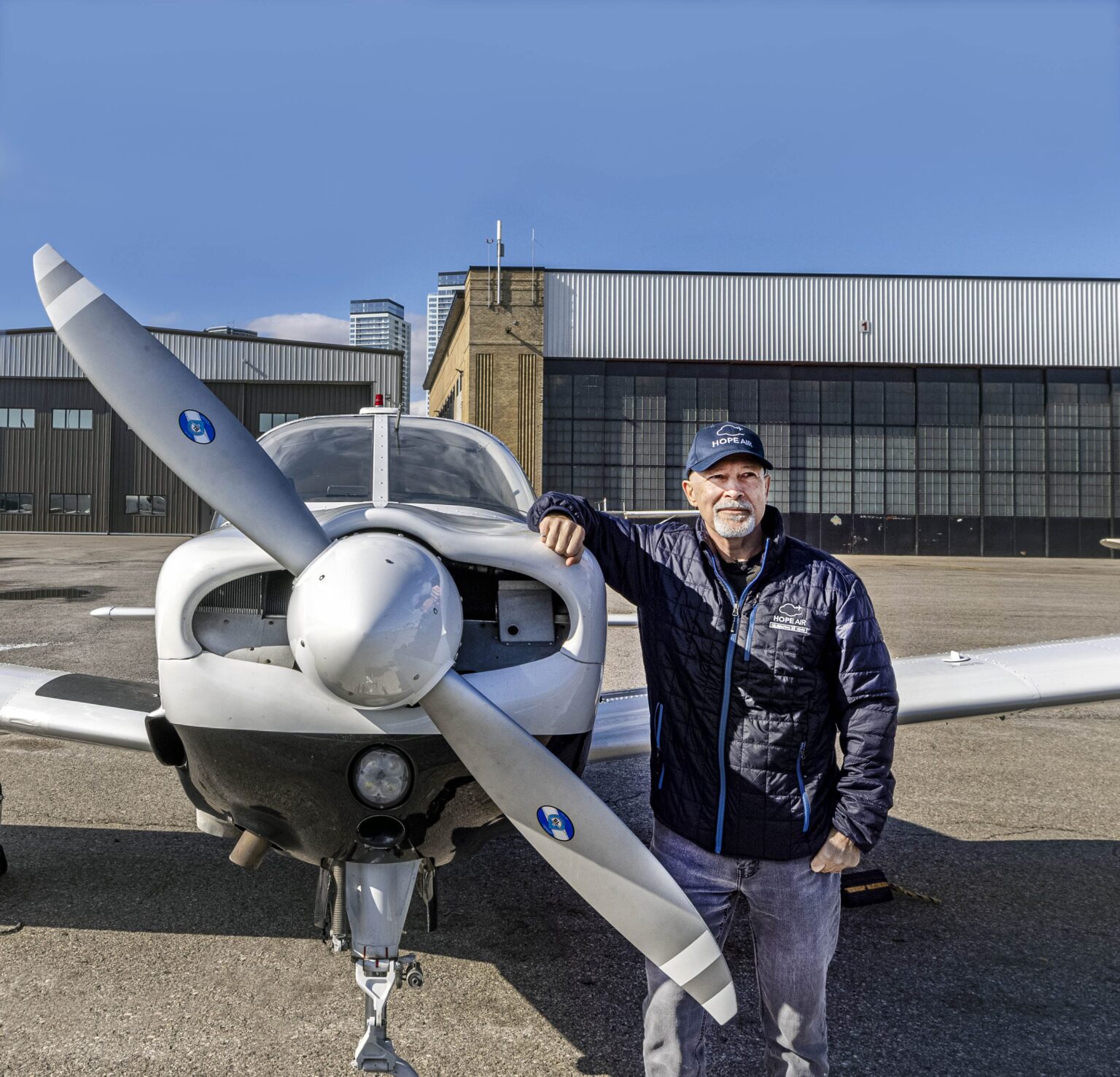 a man standing infront of a small plane, smiling