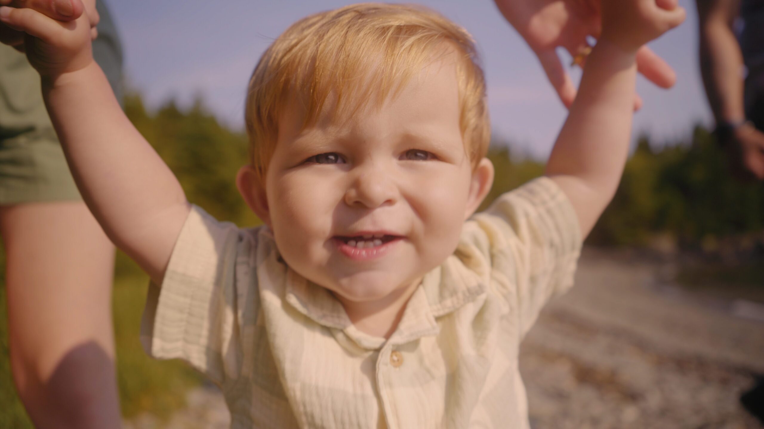 A boy holding his parents hands smiling at the camera