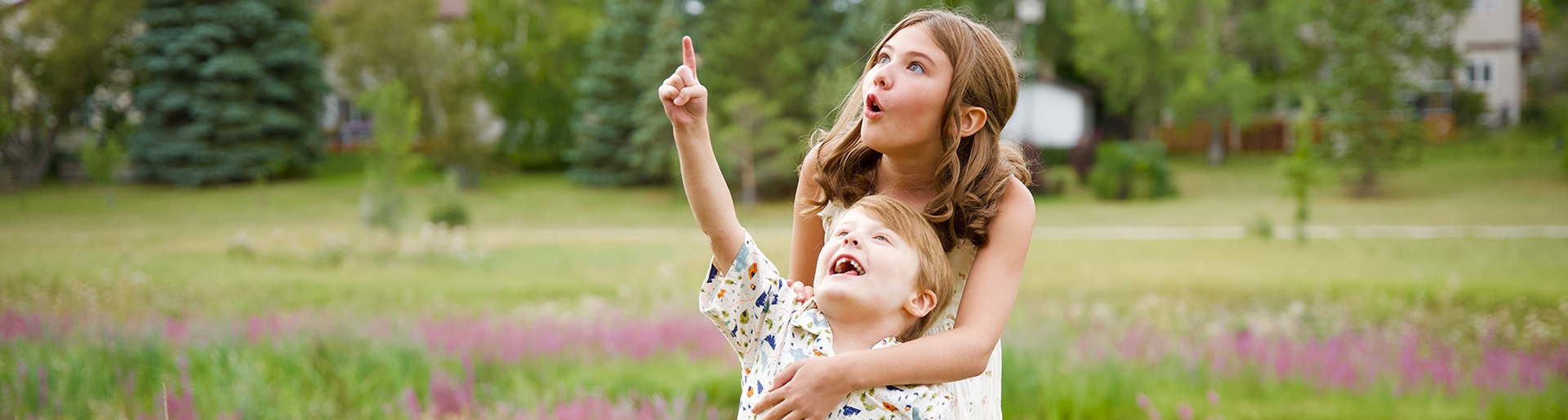 Two children smiling pointing at the sky