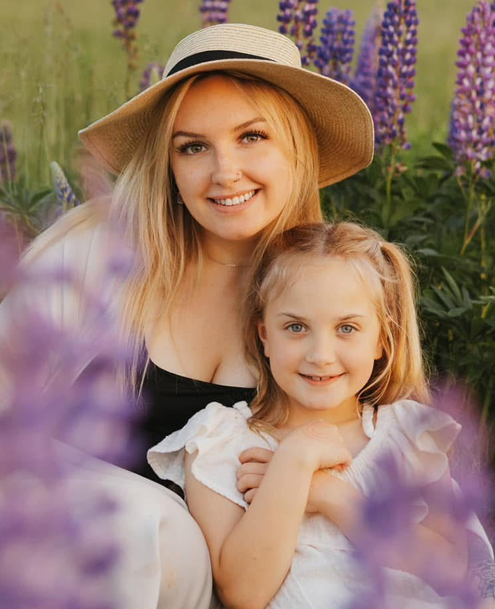 A mother and daughter smiling at the camera in a field of lavendar
