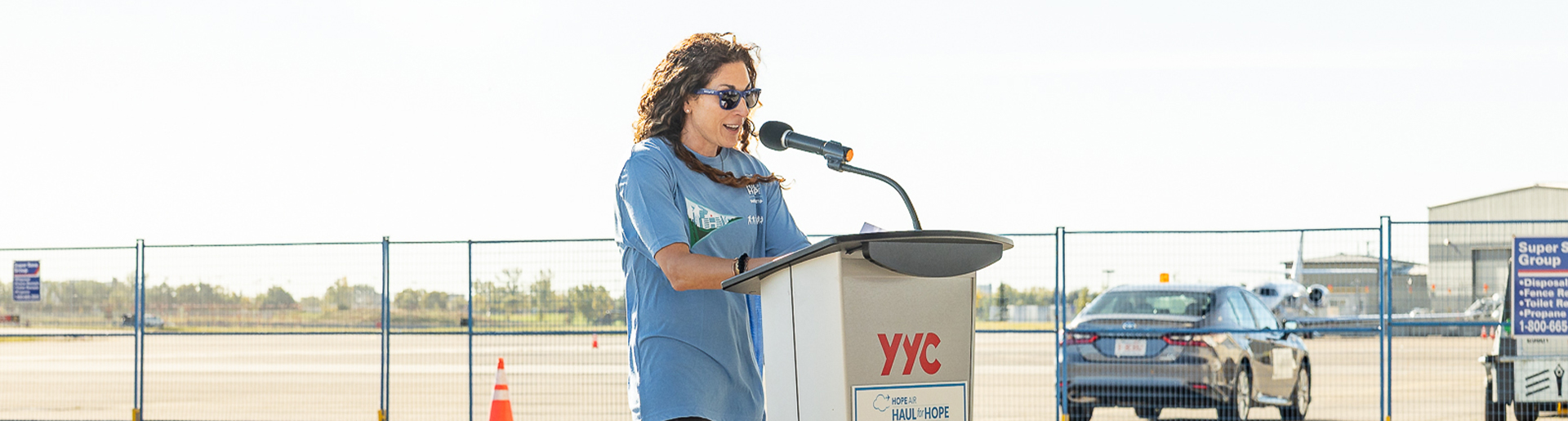 a woman in a blue shirt standing a podium giving a speech